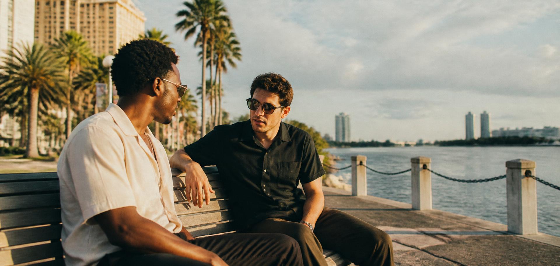 Two friends talking on a Tampa Bay waterfront bench in afternoon light
