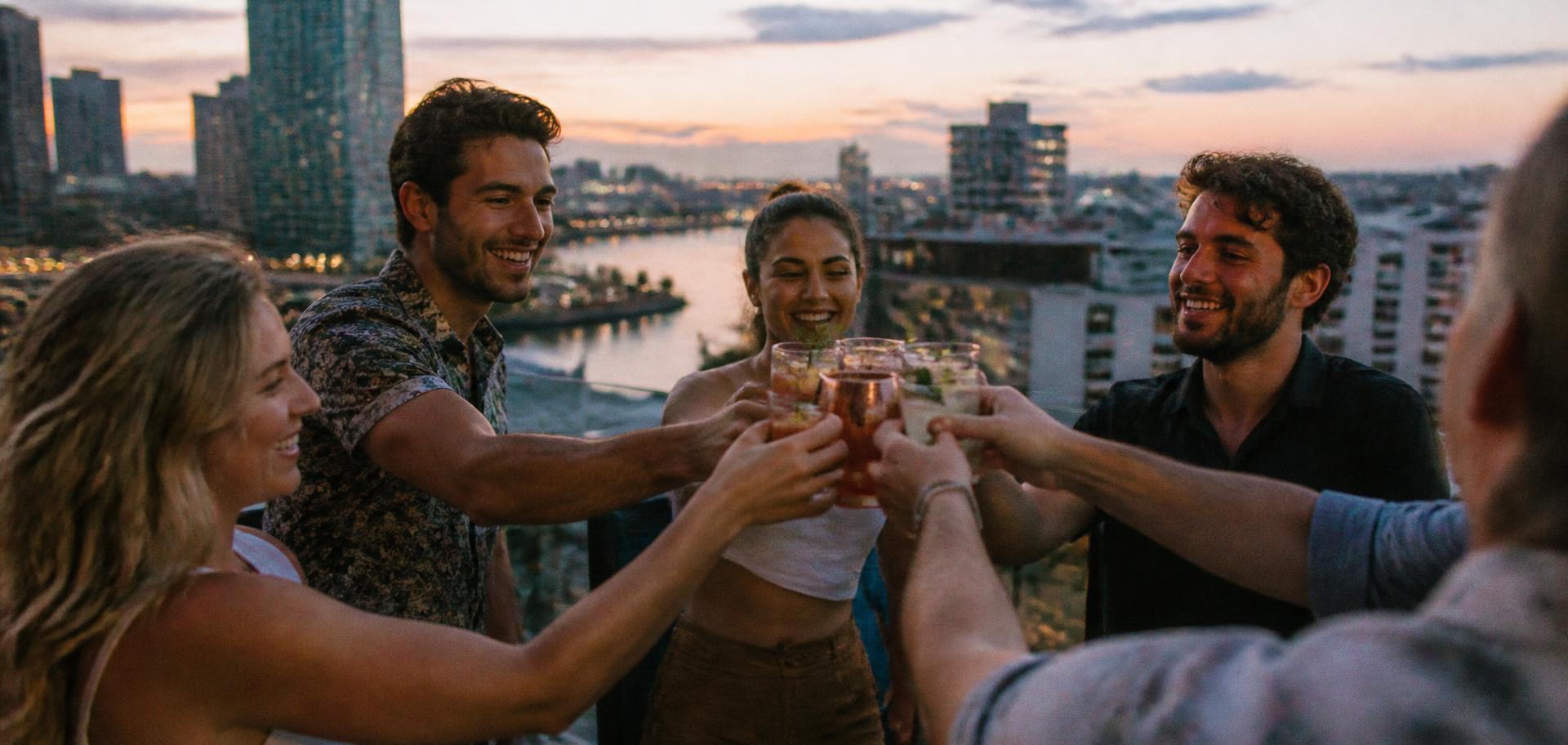 Friends toasting together at a rooftop gathering above Tampa Bay at dusk